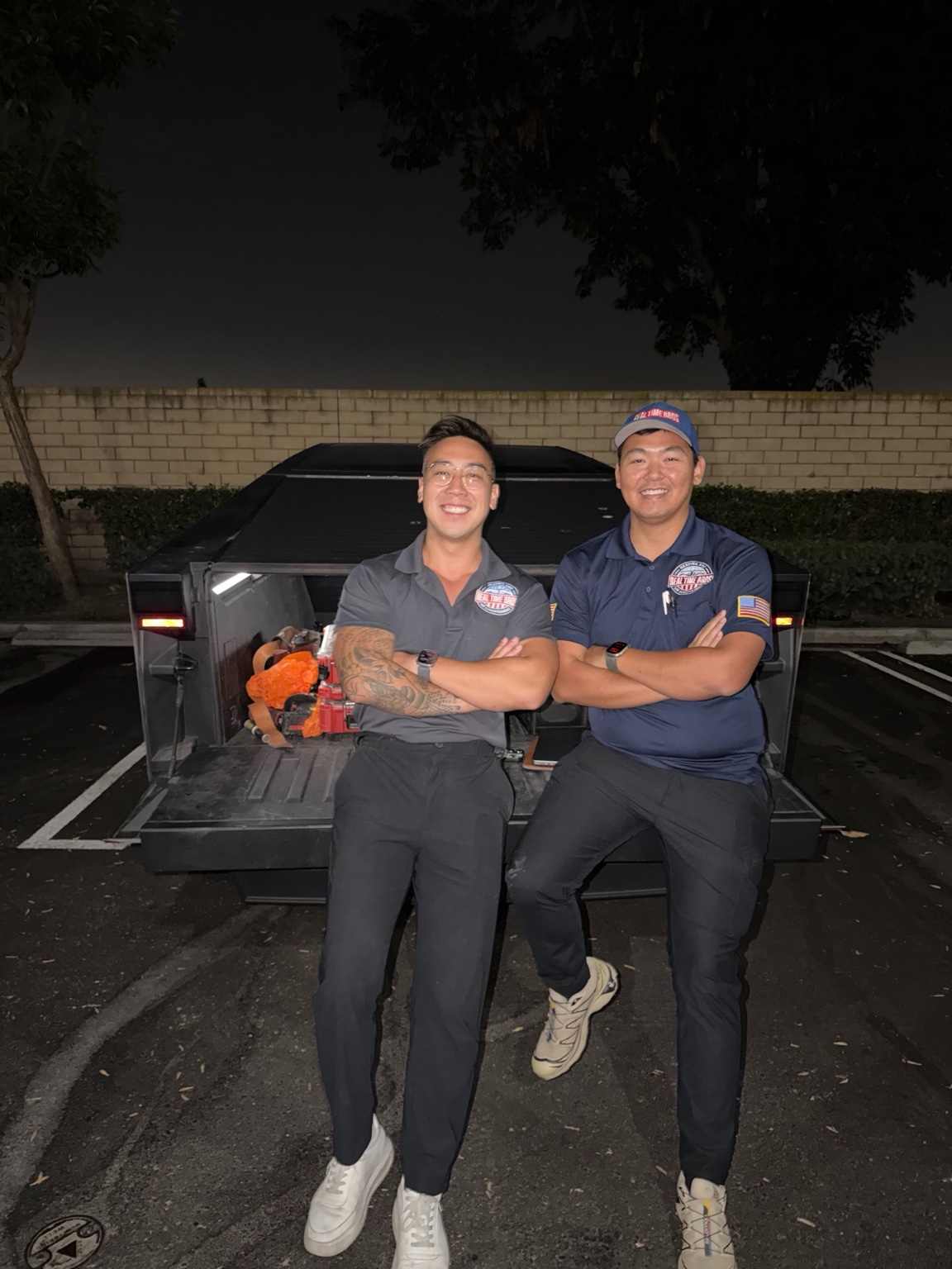 Andrew and Alvin in Real Time Bros uniforms, together at the back of their truck